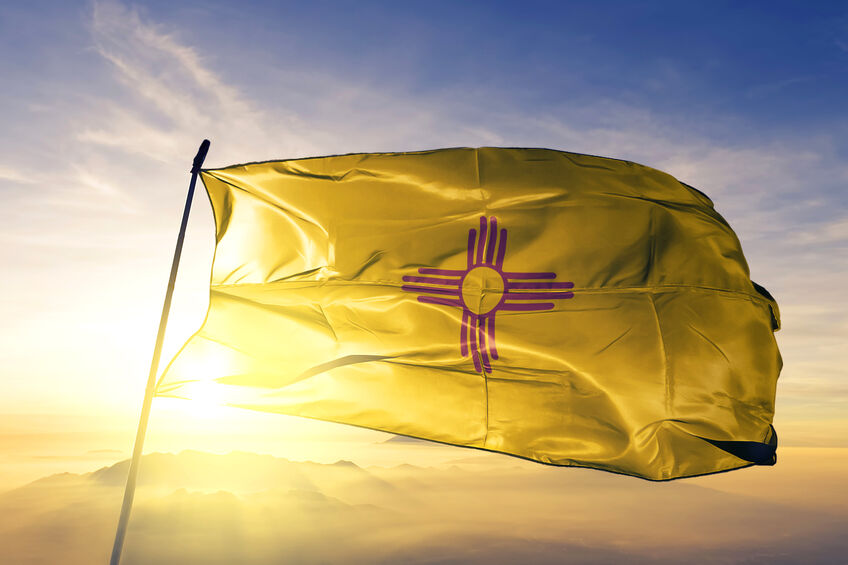 New Mexico Flag With Sun and Blue Skies Behind It